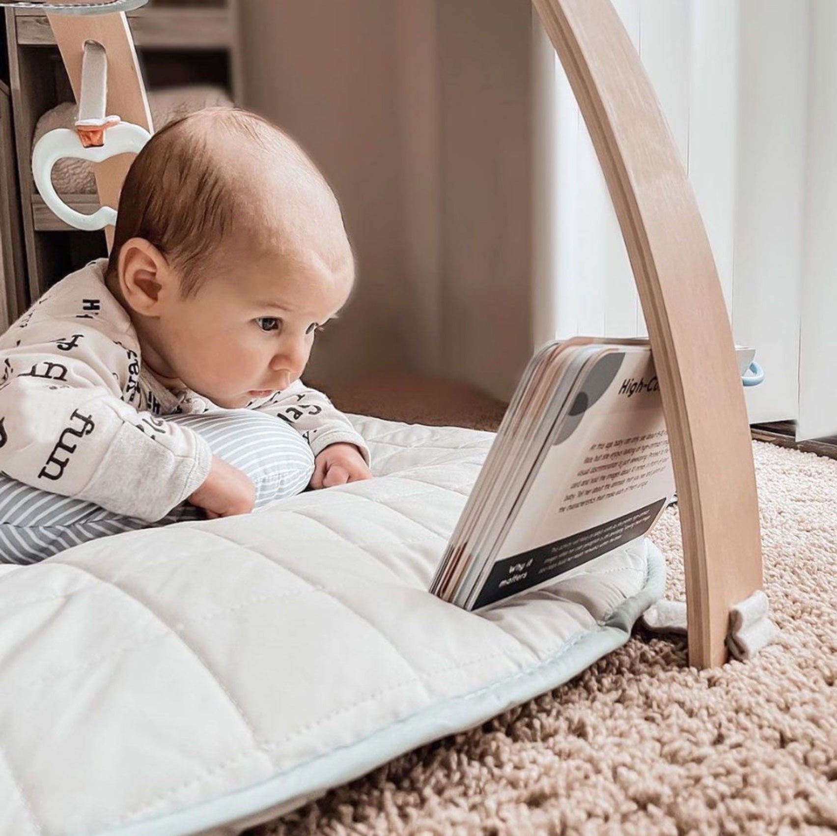 Baby on a play mat looking at a Curious Baby activity card